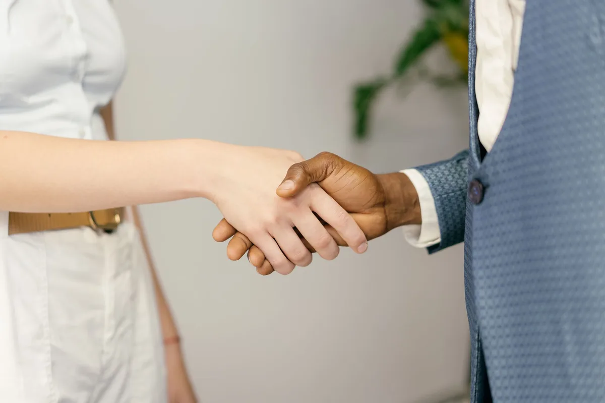Two business professionals shaking hands over a desk