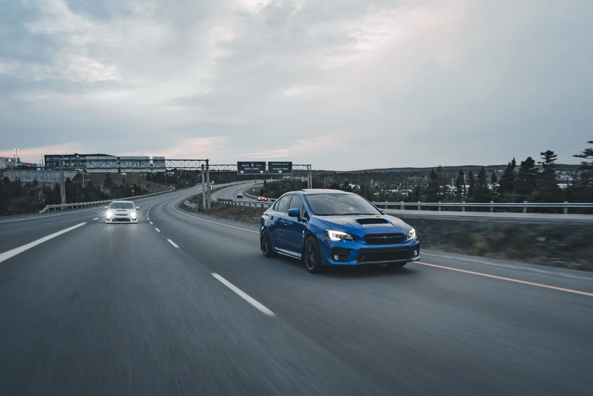 A car driving on an open road, representing summer road trip preparation
