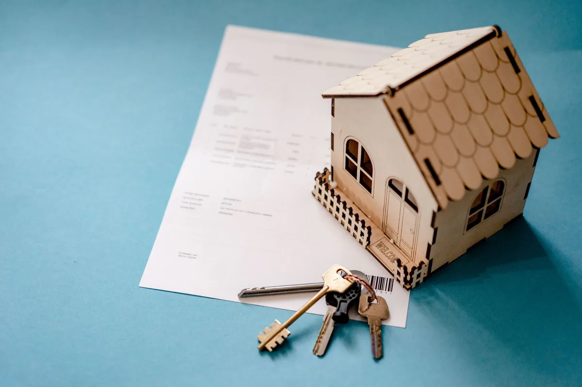 House keys on a contract document being signed, representing rental property ownership and landlord insurance