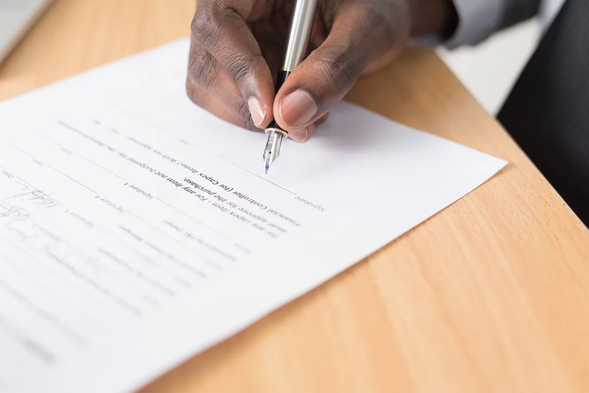 Person signing an insurance policy document with a pen