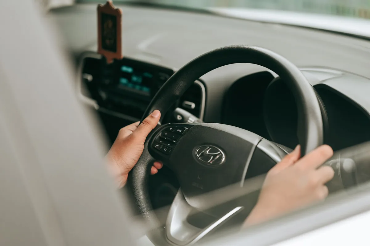Person driving a car with hands on the steering wheel