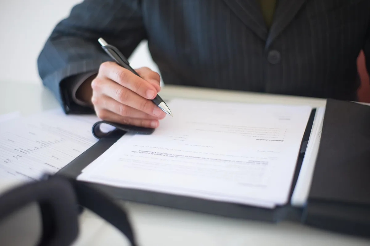 Business documents and pen on desk representing workers compensation paperwork