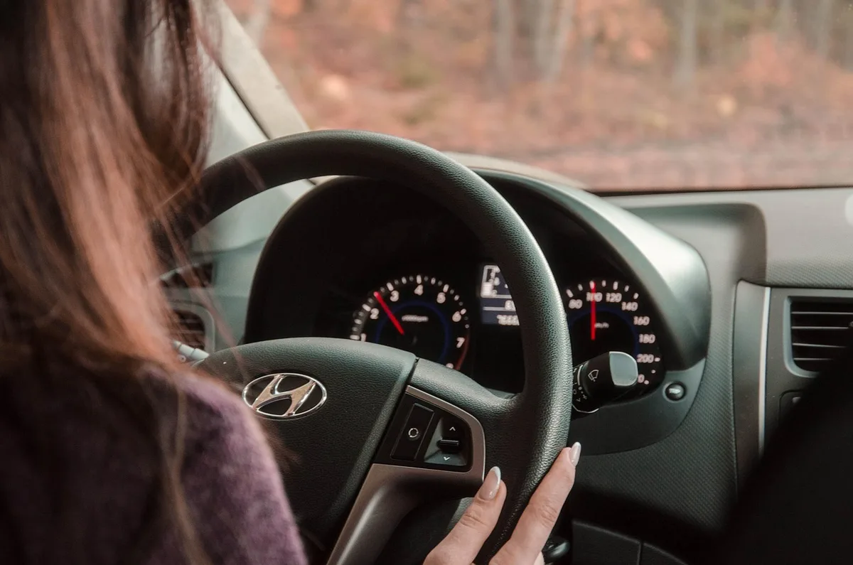 Person driving a car, hands on steering wheel
