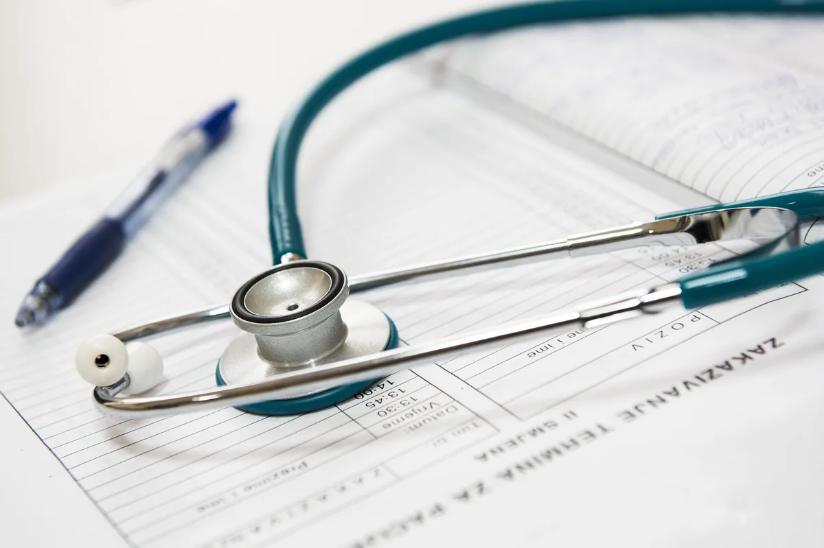 Health insurance paperwork and stethoscope on desk