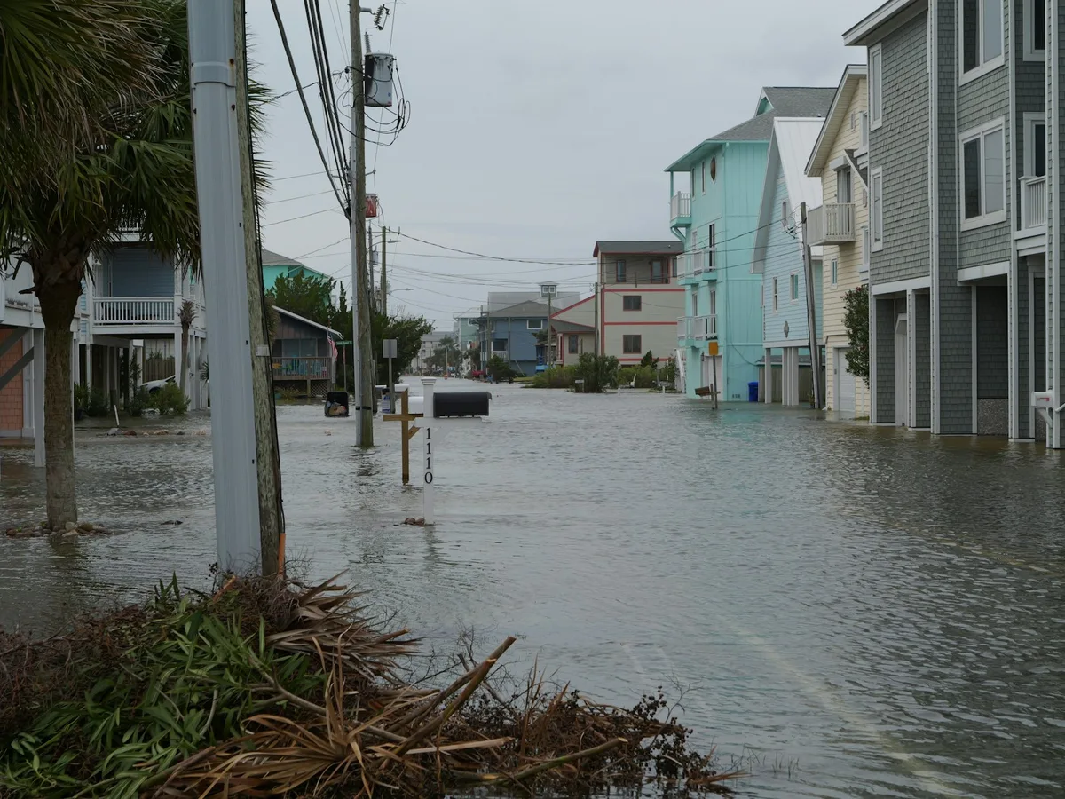 A residential street flooded with water after heavy rainfall, showing climate-related property damage