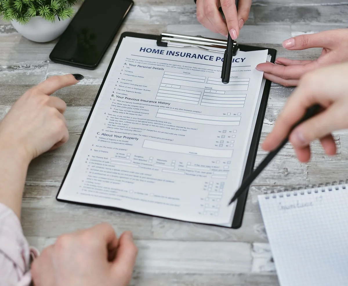 Home insurance policy document with house keys on a wooden table