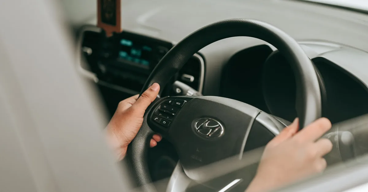Person sitting in the driver's seat of a car holding the steering wheel