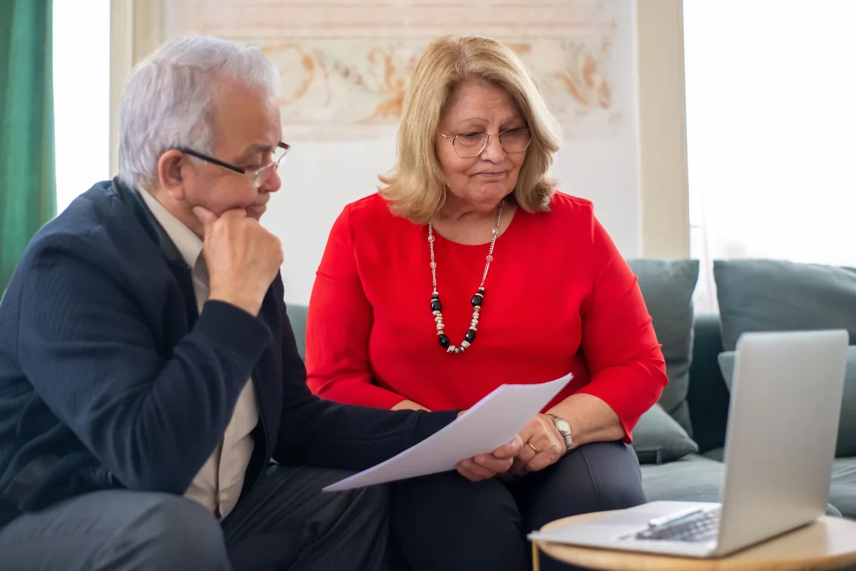 Elderly couple reviewing life insurance documents together at home