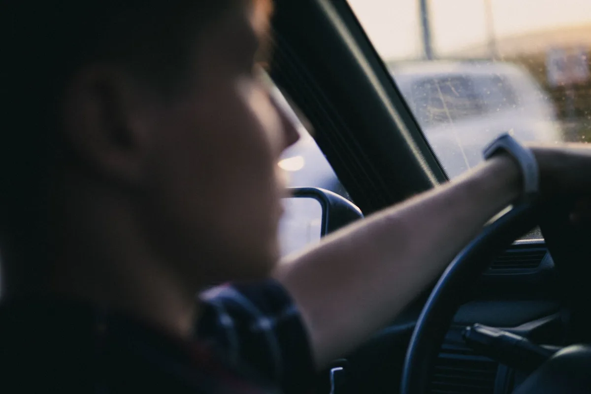 Person holding a car steering wheel while driving