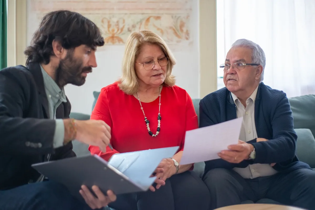 A family sitting together on a sofa reviewing financial documents