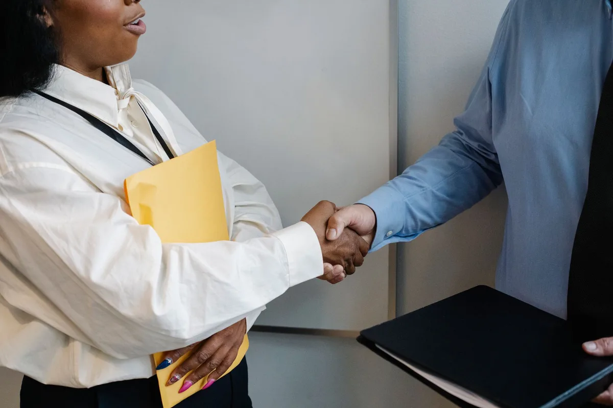 Two business professionals shaking hands over a desk