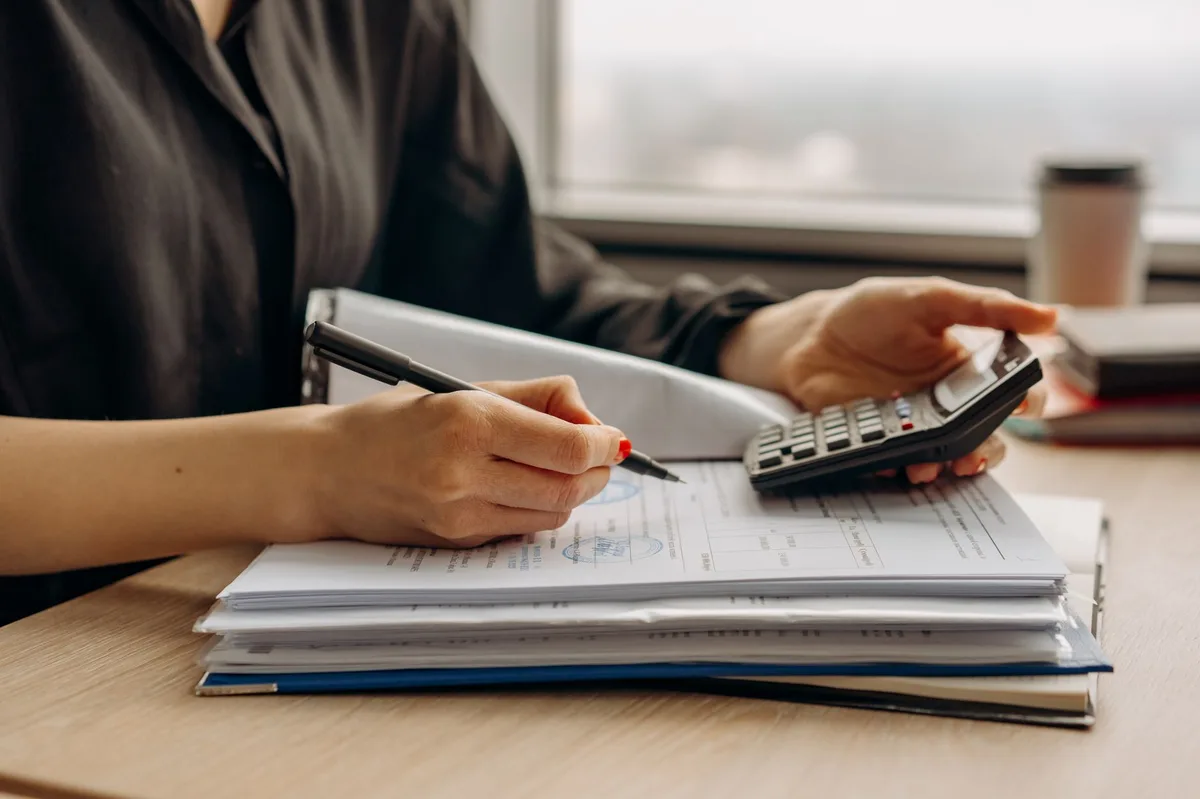 Person reviewing insurance policy documents with a pen on a wooden desk