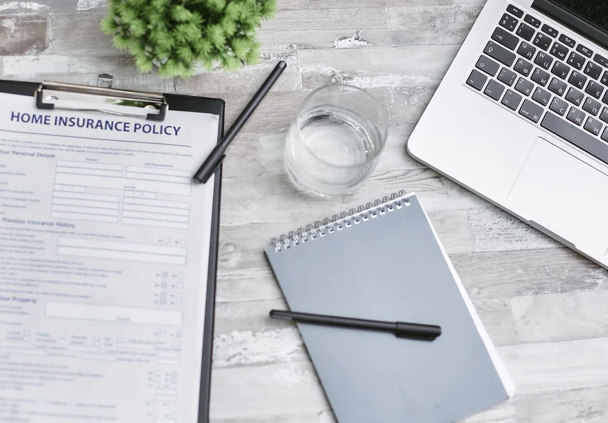 Person reviewing insurance documents with pen on desk