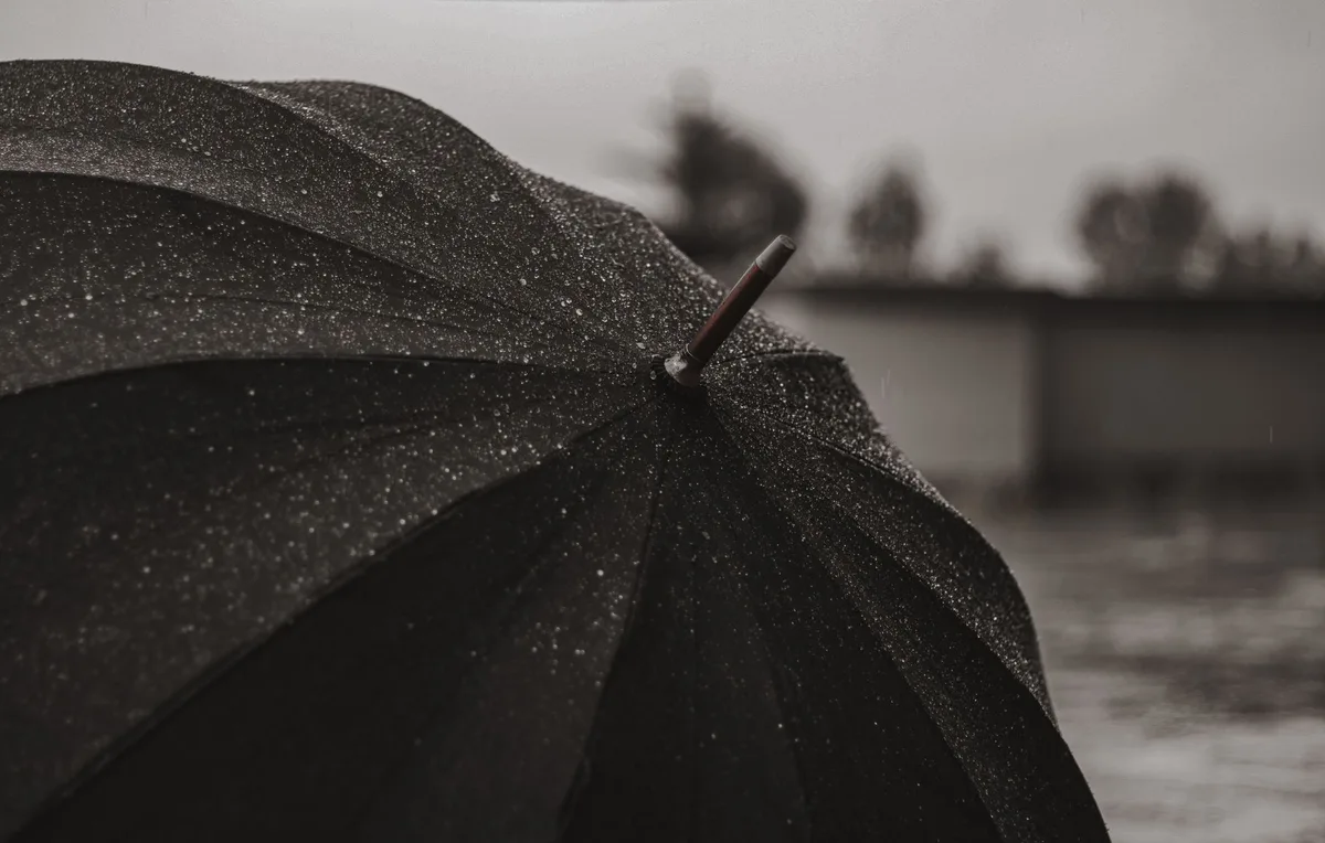 A black umbrella protecting against rain, symbolizing personal umbrella liability coverage