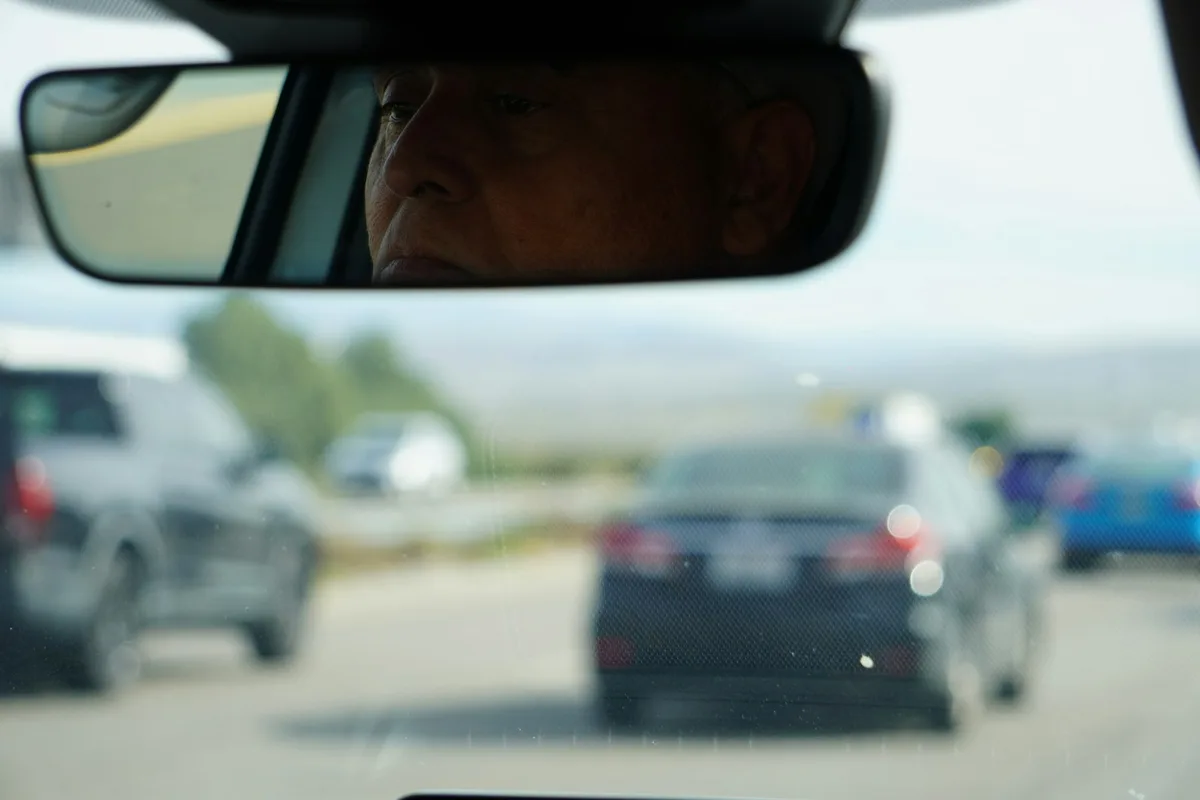 Person sitting in driver's seat of car adjusting mirror