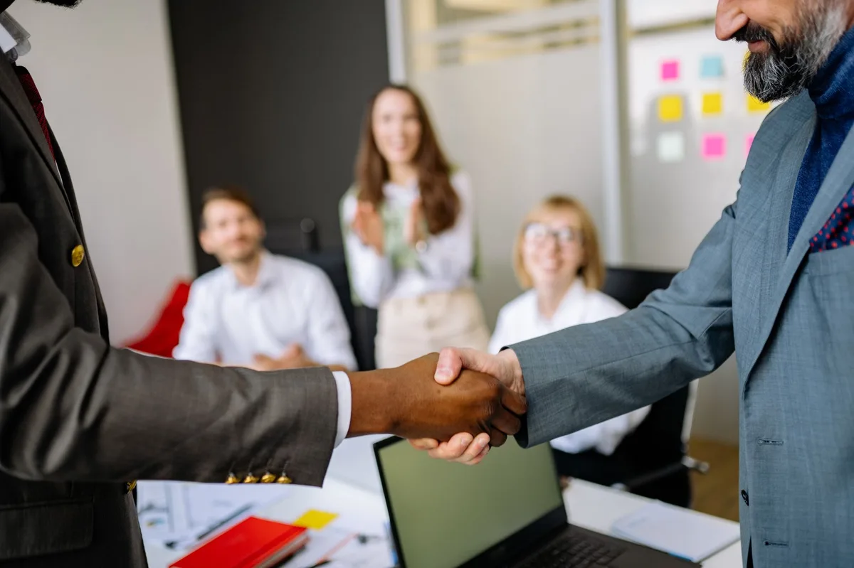 Two business professionals shaking hands in an office setting